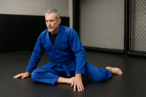Brazilian Jiu-Jitsu athlete in blue gi performing 90/90 hip mobility position to improve hip rotation
